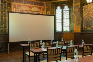 een kamer met tafels en stoelen en een groot scherm bij The Abbey Inn & Spa in Peekskill