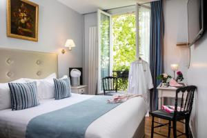 a bedroom with a bed and a desk and a window at Hotel Plaza Elysées in Paris