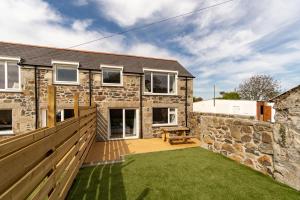 a stone house with a garden and a wooden fence at Arrowan Common Farm Cottages in Coverack