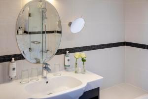 a white bathroom with a sink and a mirror at Hotel Plaza Elys&eacute;es in Paris