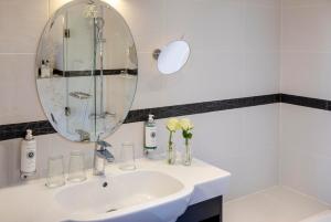 a white bathroom with a sink and a mirror at Hotel Plaza Elysées in Paris