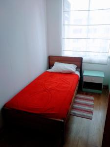 Un pequeño dormitorio con una cama roja y una ventana en Kingui, en Santiago
