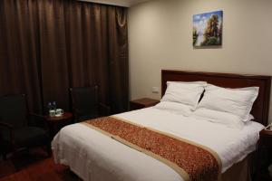 a bedroom with a large bed with white sheets and pillows at GreenTree Inn Zhangjiakou Yu County Bus Station Business Hotel in Xiaowa