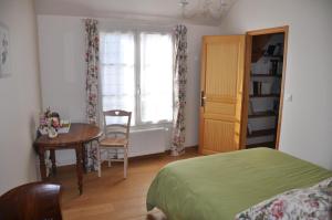 a bedroom with a bed and a table and a window at Maison Vérosia in Saint-Loup-de Naud