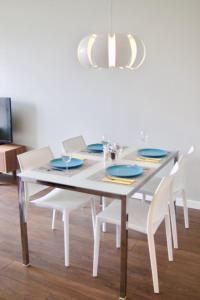 uma mesa de jantar branca com pratos e cadeiras azuis em Lotus Loft em Victoria