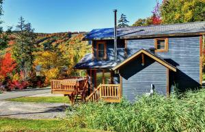 a blue house with a porch and a deck at Chalets Alpins - 12 Chemin Alpin in Stoneham