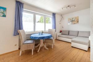 sala de estar con sofá, mesa y sillas en Alpenflora Ferienwohnungen en Ofterschwang