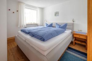 een blauw en wit bed in een slaapkamer met een raam bij Alpenflora Ferienwohnungen in Ofterschwang