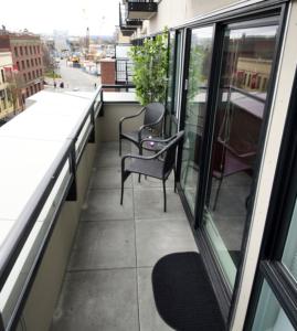 a balcony with two chairs and a view of a street at Urban Den in Victoria