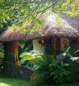 a thatch roofed house with a large painting on it at Cabañas Mannan in Tanchachín