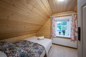 2 Betten in einem Holzzimmer mit Fenster in der Unterkunft Lipowy Zakątek i Żubry na pobliskich łąkach in Siemianówka