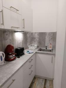 una cocina con armarios blancos y fregadero en Pompár Belvárosi Apartman, en Szeged