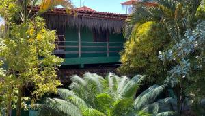 a green building with palm trees in front of it at Pousada Sossego in Ilha de Boipeba