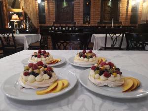 three cakes with fruit on plates on a table at Hotel Sumski Feneri in Bitola