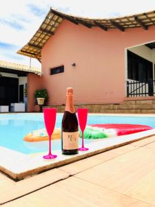 a bottle of wine with two glasses next to a swimming pool at Casa de Praia Orla de Atalaia Casa da Fabi in Aracaju