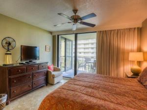 a bedroom with a bed and a television and a balcony at Mainsail II in Destin +49 photos
