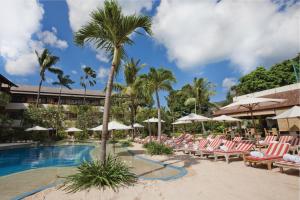 a pool at the resort with lounge chairs and palm trees at Blu-Zea Resort by Double-Six in Seminyak