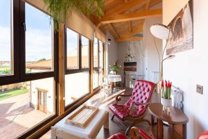 a living room with a table and chairs and large windows at La Rosaleda León - Casa Rural - in Hospital de Órbigo
