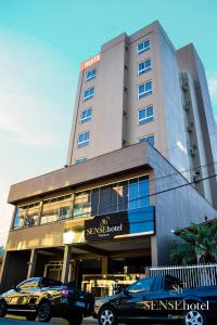 een gebouw met twee auto's ervoor geparkeerd bij Sense Hotel Premium in Capinzal
