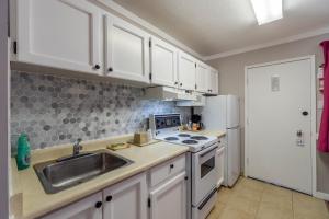 a kitchen with white cabinets and a sink and a refrigerator at Canada's Best Value Desert Inn & Suites in Cache Creek