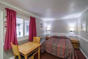 a bedroom with a bed and a desk and a table at Canada's Best Value Desert Inn & Suites in Cache Creek