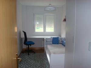 a small room with a bed and a chair and a window at PISO ALISAL CON GARAJE in Santander