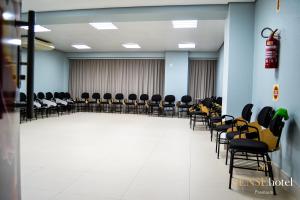 una habitación vacía con sillas y mesas y una habitación con extintor de incendios en Sense Hotel Premium, en Capinzal