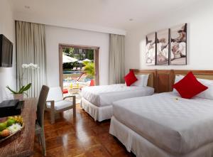 a hotel room with two beds and a table with a bowl of fruit at Blu-Zea Resort by Double-Six in Seminyak