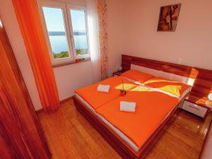 a bedroom with a bed with orange sheets and a window at Beautiful Apartment in Dramalj in Dramalj