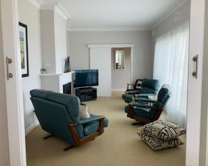 a living room with three chairs and a television at Jewel of the South Beachfront Holiday Rental in Tumby Bay