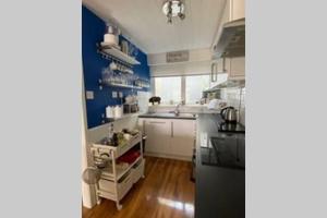 a kitchen with white cabinets and a blue wall at The Little Boat House in Talsarnau