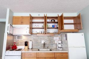 a kitchen with wooden cabinets and a white refrigerator at Waikiki Place Studios at The Marine Surf Waikiki in Honolulu