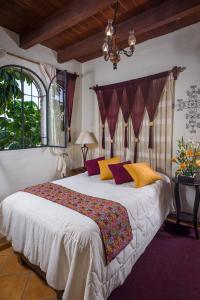sypialnia z dużym łóżkiem z żółtymi i fioletowymi poduszkami w obiekcie Hacienda La Moreda Hotel Boutique & Spa w mieście Guadalajara