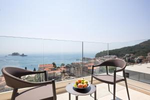two chairs and a bowl of fruit on a table on a balcony at Hotel AMI Budva Petrovac in Petrovac na Moru
