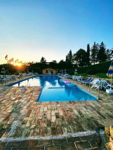 a large swimming pool with chairs and umbrellas at Agriturismo Comparone Casavecchia in Città di Castello