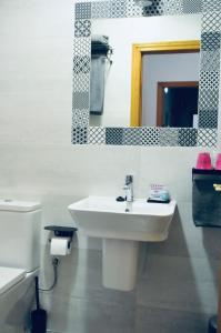 een badkamer met een wastafel, een toilet en een spiegel bij Balenax Pensión in Gijón