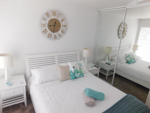 a white bedroom with a bed and a mirror at Secret at Huskisson in Huskisson