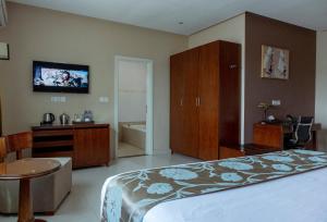 um quarto com uma cama e uma televisão na parede em Frederick's Lodge em Kumasi