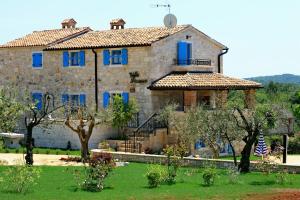 a large stone house with blue windows and a yard at Villa Simone in Žbandaj