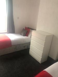 a bedroom with a bed with a dresser and a window at Kirubash Central Pier Hotel in Blackpool