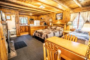 a log cabin bedroom with two beds and a kitchen at Colorado Bear Creek Cabins in Evergreen
