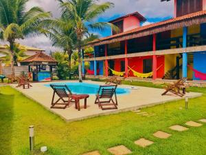 a resort with a pool and chairs and a building at Pousada Perola da Barra in Barra Grande