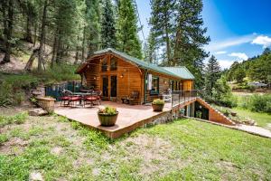 a log cabin in the woods with a deck at Colorado Bear Creek Cabins in Evergreen