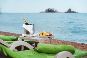 a table with a bottle of wine and fruit on the beach at Hotel AMI Budva Petrovac in Petrovac na Moru