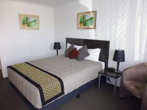 a bedroom with a bed and a couch and a table at Burke & Wills Motor Inn in Kingaroy