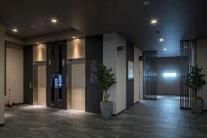 a hallway with two potted plants in a building at Hotel Route-Inn Kamisu in Kamisu