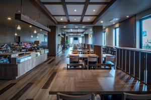 een restaurant met houten tafels, stoelen en ramen bij Hotel Route-Inn Kamisu in Kamisu