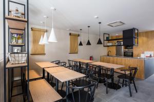 a restaurant with wooden tables and chairs and a kitchen at Gallery Hostel in Porto
