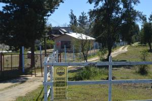 a sign on a fence in front of a house at Coyunche Cabañas y Camping Laja & San Rosendo in Laja