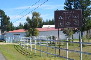 un cartel en una valla delante de un edificio en Coyunche Cabañas y Camping Laja & San Rosendo en Laja